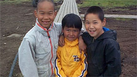 Three native boys smile for the camera.